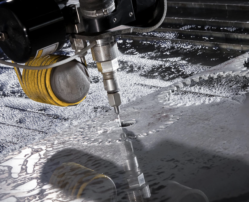 Close-up of a CNC waterjet cutting machine slicing through metal
