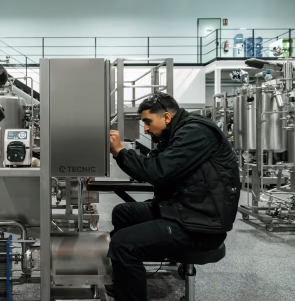 Technician working on industrial machinery control panel in a factory setting.